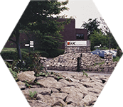 Signs and parking at FAAC headquarters. Paving in the foreground, trees in the background.